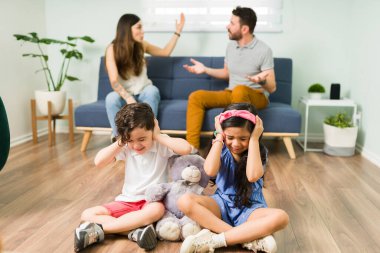 Anne, baba lütfen kavga etmeyi kesin. Kızgın ebeveynleri ilişki sorunları yüzünden bağırıp kavga ederken üzgün çocuklar kulaklarını kapatıyor. 