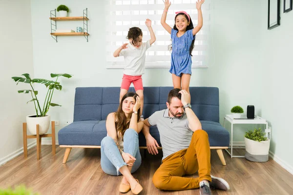 私たちはとても疲れている 彼らの小さな子供たちが間違っているとソファの上でジャンプしているので ストレスを感じる親 — ストック写真