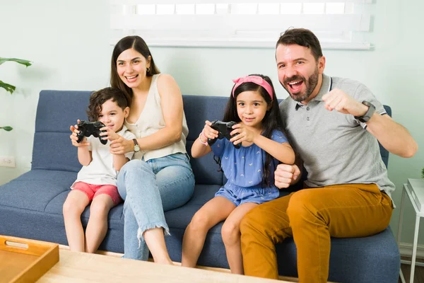 有很多的乐趣 快乐可爱的孩子们一边和快乐的父母一起玩电子游戏 一边在家里享受闲暇时光 — 图库照片
