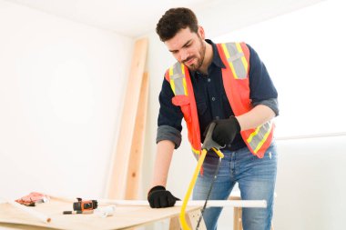 Yeni boru hatlarını testereyle kesen mutlu erkek müteahhit. İnşaat alanında çalışan İspanyol tesisatçı. 