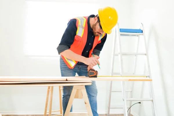 Focused Young Man Measuring Wooden Panel Building New Wall Home — Stockfoto