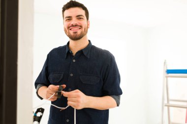 Endüstriyel bantla tamir ederken gülümseyen ve göz teması kuran İspanyol bir işçinin portresi.