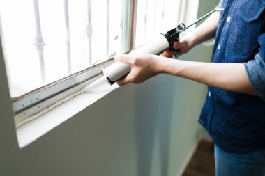 İspanyol bir adamın evindeki pencereye yalıtım malzemesi koymasına yakın çekim. Delikanlı ev tamiri yapıyor. 