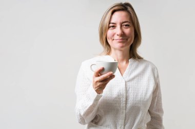 Kahvaltıdan önce kahvenin tadını çıkarıyorum. Çekici orta yaşlı kadın bir fincan sıcak kahve içerken gülümsüyor ve göz teması kuruyor.