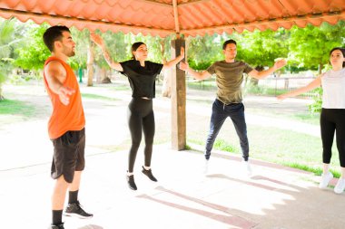 Çekici İspanyol ve Kafkas genç arkadaşları dışarıda kardiyo egzersizi yaparken zıplama hareketleri yapıyorlar.