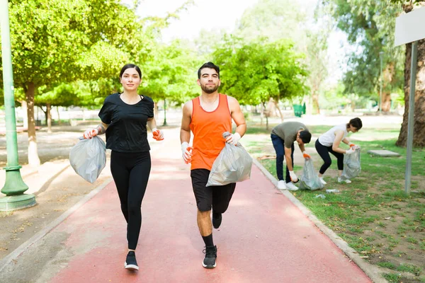 Attractive Latin Couple Holding Trash Bags Garbage While Running Group — Stock Photo, Image