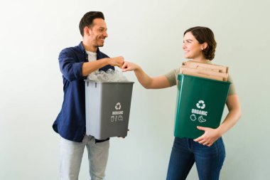 Heyecanlı genç kadın ve erkek yumruk tokuşturuyor. Sorumlu çift evde plastik ve kartondan geri dönüşüm yapıyor. 
