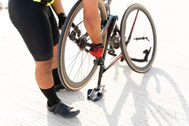 Bozuk bisikletimi tamir ediyorum. Patlak bir lastiği tamir ederken bisiklet şortu ve eldiveni olan genç bir adama yaklaş.