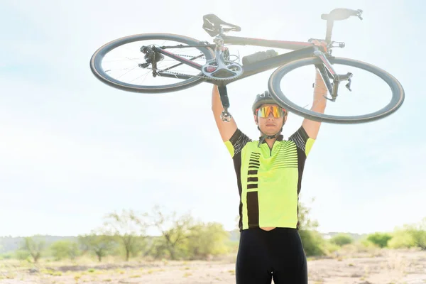 骑自行车的职业男性骑手将自行车抬过头顶 庆祝他的职业生涯结束 — 图库照片