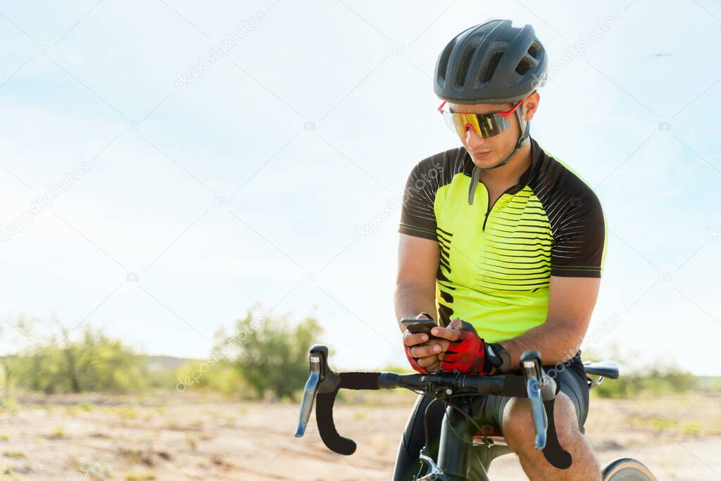 Checking my phone while exercising. Attractive young athlete texting while making a stop from cycling on an open road