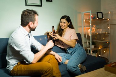 Çekici genç bir kadın birlikte bira içerken erkek arkadaşıyla konuşuyor. Geceleri kanepede dinlenen güzel bir çift.