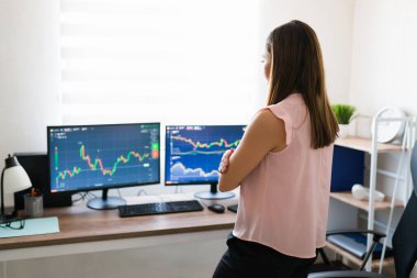 İspanyol iş kadını çalışma masasının önünde durup bilgisayarındaki borsayı kontrol ederken görülmüş.