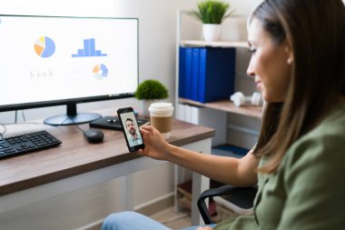 Güzel genç bir kadın, evde yönetici olarak çalışırken iş arkadaşıyla ya da iş arkadaşıyla telefon görüşmesi yapıyor.