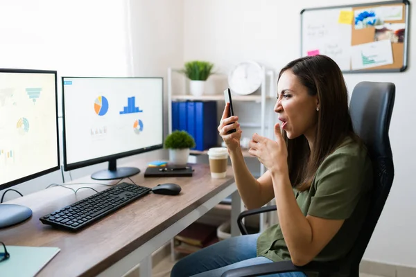 Work mistake. Business manager screaming and feeling angry towards a co-worker during an online video call on her smartphone