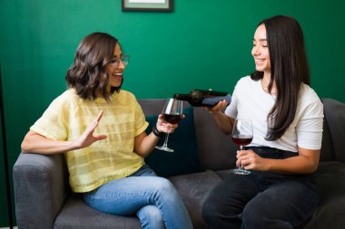 Takılmayı seviyoruz. Evdeki dedikodulardan bahsederken en iyi arkadaşına bir bardak kırmızı şarap servis eden güzel genç bir kadın.