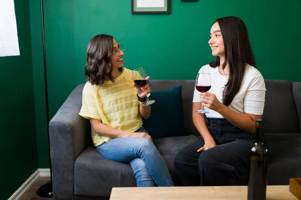 一緒にワインを飲みながら素敵な会話をしている魅力的な若い女性とリビングルームでぶらついて — ストック写真
