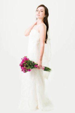 Enfes bir gelinlik ve elinde çiçek buketi tutan güzel bir peçeyle çekici genç bir gelin. 