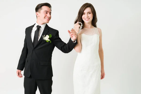 我抓住他了婚礼当天 身穿白衣的快乐的妻子笑着把手铐戴在幸福的丈夫身上 — 图库照片