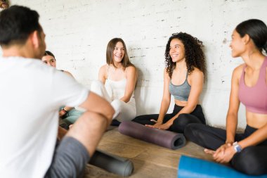 Çekici İspanyol kadın birlikte dersi bitirdikten sonra bir grup insanla yoga rutini hakkında konuşuyor.