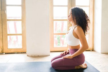 Stüdyoda yoga yaparken şimşek pozu veren gevşemiş İspanyol kadın.