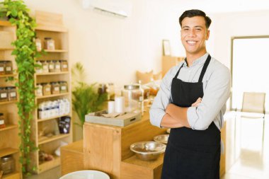 Neşeli girişimci kameraya bakıp gülümserken kendi sıfır atık marketini işletmekten gurur duyar.