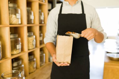 Satılık kahverengi bir çantaya koymak için ceviz toplayan bir çalışanın fotoğrafını çek. Delikanlı toptancı dükkanında fındık ve tahıl satıyor.