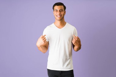 Beni seç, ben en iyisiyim. Latin genç adam gülümsüyor ve mutlu hissederken kendini işaret ediyor. 