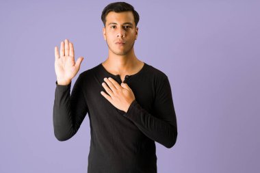 Tüm kalbimle yemin ederim. Sadık genç bir adam, kalbinde bir diğeriyle el kaldırırken yemin ediyor. 