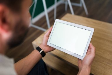 Yetişkin bir adamın dijital tabletini kullanarak fotokopi alanı olan boş bir ekrana baktığını düşün. 