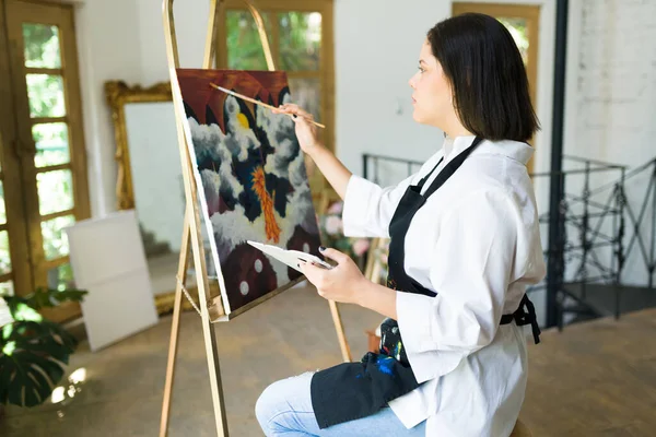 创造一个艺术品 才华横溢的女画家正在画一幅漂亮的画 用画笔和调色板的年轻女人 — 图库照片