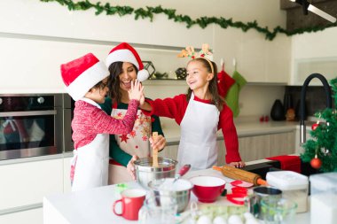 Çak bakalım! Sevimli kardeşler mutlu anneleriyle kurabiye pişirirken beşlik çakıp kutlama yapıyorlar.