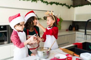 Seni seviyorum anne. Güzel küçük kız annesinin burnuna hamuru yerleştiriyor ve kurabiye pişirirken eğleniyor.