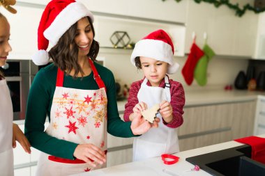 Kurabiye alabilir miyim? Mutlu genç anne, Noel 'de yemek pişirirken oğluna kurabiye veriyor.