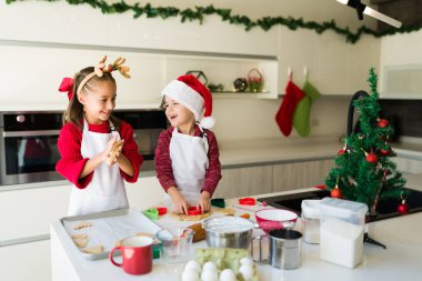 Küçük kız ve oğlan, Noel 'de mutfakta kurabiye hamuru karıştırırken eğlenirken gülüyorlar.