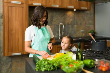 Annesinden çorba ve salata pişirmeyi öğrenen tatlı bir kız. Aile yemeği hazırlıyor 