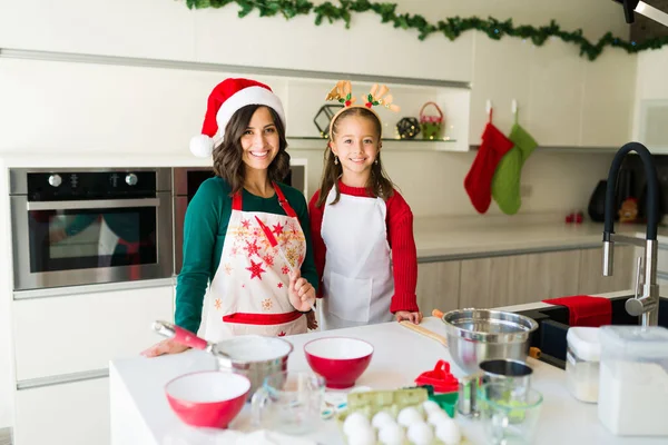 美しい若いお母さんと娘は笑顔とキッチンでクリスマスクッキーを作りながら カメラを見て — ストック写真