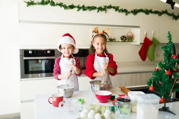 We love baking cookies. Happy little boy and girl making eye contact while baking christmas cookies for the family