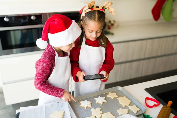 Schöne Kinder Schürzen Fotografieren Mit Dem Smartphone Die Gebackenen Weihnachtsplätzchen — Stockfoto