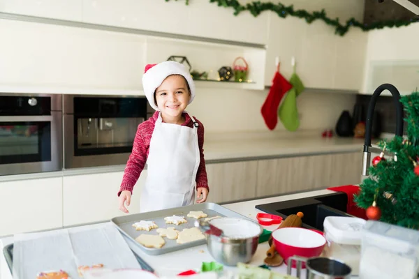 幸せなCaucasian男の子とともにAサンタ帽子見てカメラと笑顔ながら準備クリスマスクッキー — ストック写真