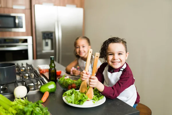 Roztomilý Malý Chlapec Připravuje Zelený Salát Svou Sestrou Zároveň Pomáhá — Stock fotografie