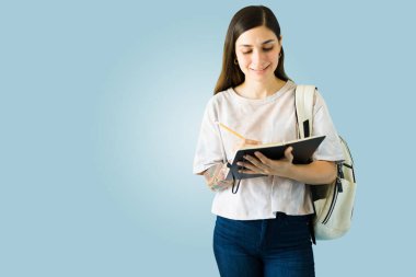 Akıllı üniversite öğrencisi ödevleri için not alıyor. Latin genç kadın yazıyor ve okuyor. 