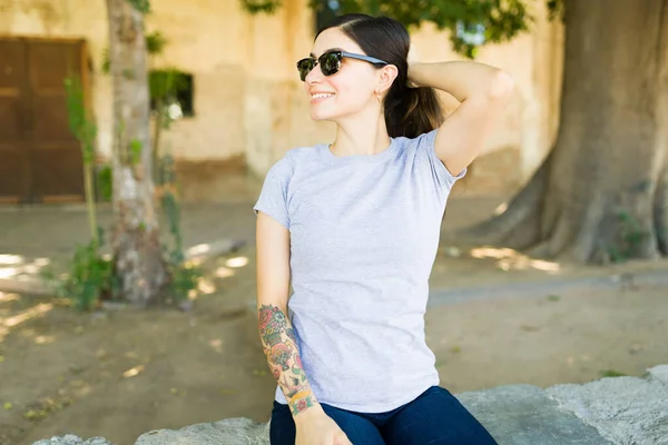 綿グレーのTシャツを着て 暑い日に屋外でポニーテールを作るスタイリッシュな女性 — ストック写真