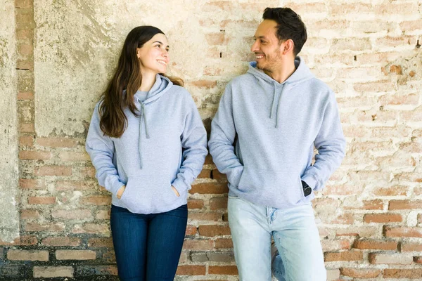 魅力的なカップルは グレーのマッチングカスタムプリントスウェットシャツを身に着けている間 お互いを見て笑顔 — ストック写真