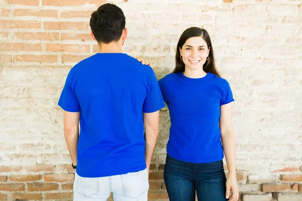 Hermosa Pareja Hispana Vistiendo Camisetas Azules Juego Mientras Muestra Diseño —  Fotos de Stock