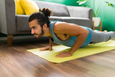 Dört bacaklı personel pozu. Aktif giyimli güçlü genç adam evde yoga egzersizleri yapıyor.