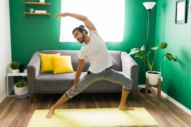 Savaşçı yoga pozunda sportif, mutlu bir genç adam. Latin bir adamla dinleniyor.