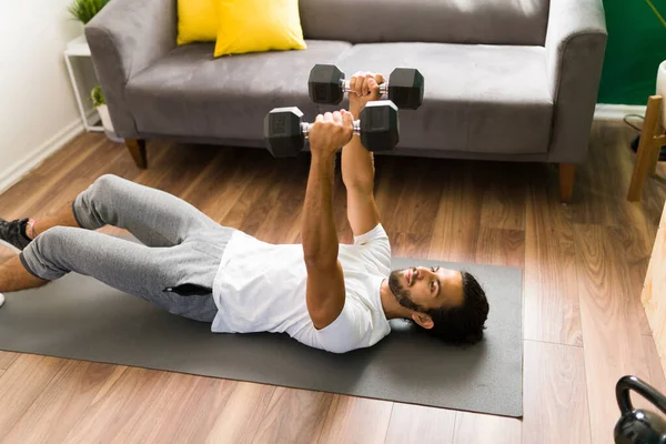 Красивый Латиноамериканец Тренируется Дома Поднимает Два Веса Лежа Коврике Упражнений — стоковое фото