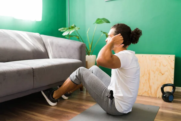 一个健康的恐慌男人在家里训练和做腹肌挤压的后视镜 — 图库照片