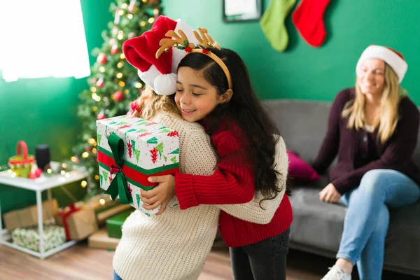 Thank you so much. Cute hispanic daughter hugging her mom for giving her a Christmas present