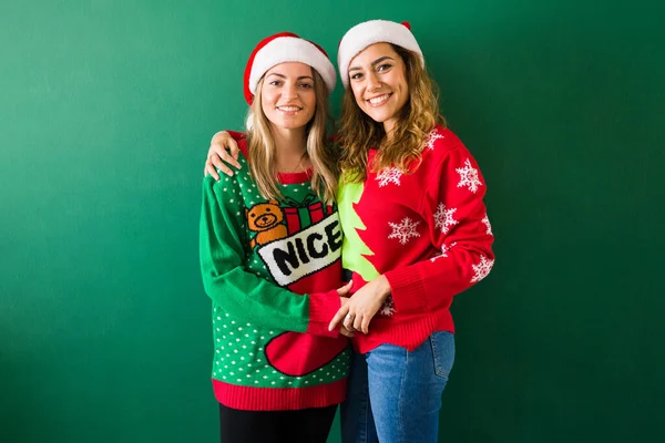 Smiling Gorgeous Gay Women Santa Hats Christmas Sweaters Hugging Green — Stock Photo, Image